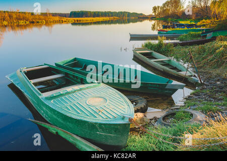 Close View Of Moored Green Wood Angel Ruderboote Skippets Auf Dem Bewegungslosen Wasser Am Herbstfall Ufer Des Flusses. Stockfoto