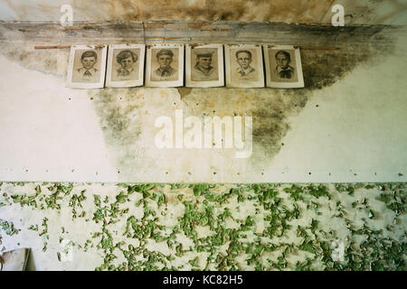 Sechs Schwarzweißpapierporträts der jungen Pioniere, Helden des Zweiten Weltkriegs auf der zerrissenen Peeling Wall im Klassenzimmer der verlassenen Schule nach Tschernobyl Nucl Stockfoto