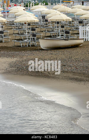Boot gelandet, Sonnenschirme und Liegestühle am leeren Strand Resort, in hellen Spätsommer licht Schuß am Mittelmeer, touristisches Dorf von sestri Leva Stockfoto