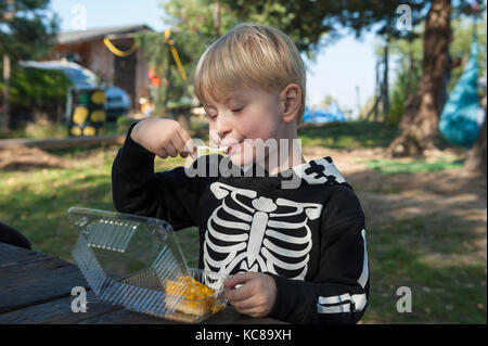 Junge in Skelett Kostüm essen Pumpkin Pie Stockfoto