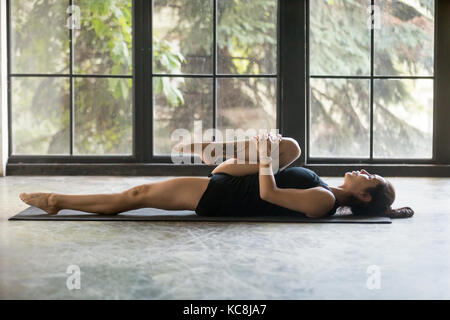 Junge attraktive Frau in die Knie zur Brust darstellen, studio Hintergrund Stockfoto