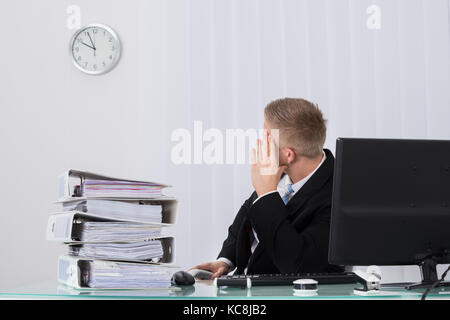 Junge männliche Unternehmer Schauen auf die Uhr im Büro Stockfoto