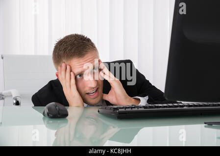 Verängstigte junge Unternehmer auf der Suche am Computer im Büro Stockfoto