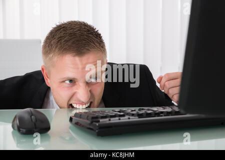 Wütende junge Geschäftsmann auf Computer im Büro Stockfoto