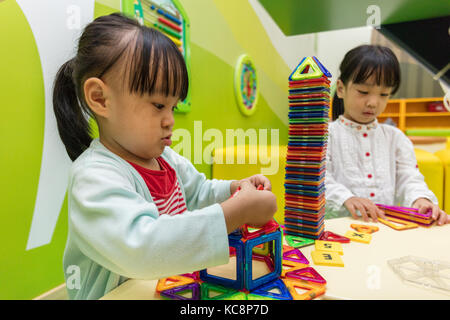 Asiatische chinesische Mädchen spielen bunt magnet Kunststoff Bausteine Kit bei Indoor Spielplatz Stockfoto