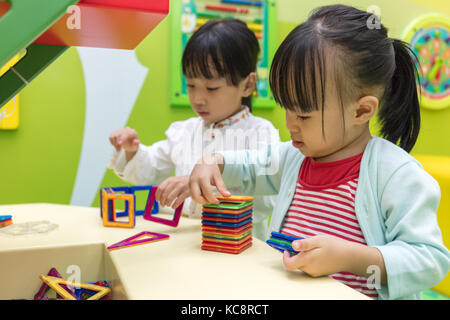 Asiatische chinesische Mädchen spielen bunt magnet Kunststoff Bausteine Kit bei Indoor Spielplatz Stockfoto