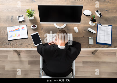 Junge Unternehmer schlafen auf dem Schreibtisch im Büro Stockfoto