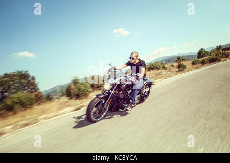 Junger Mann auf einem Motorrad auf eine offene Straße Stockfoto