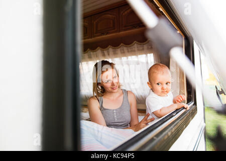Schöne junge Mutter und ihr Baby Sohn in einem Wohnmobil im Sommer Stockfoto