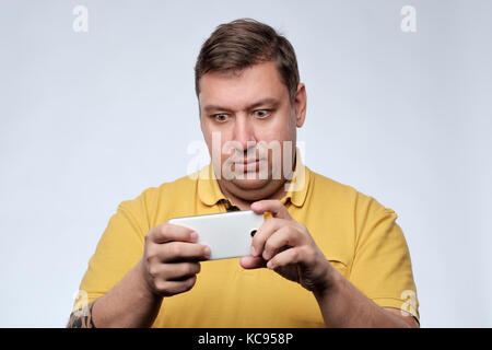 Ein Porträt von überrascht junge fetter Mann mit Handy. Stockfoto