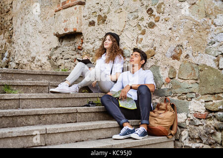 Zwei schöne junge Touristen mit Karte in der Altstadt. Teenager sitzen auf Treppen, ausruhen. Stockfoto