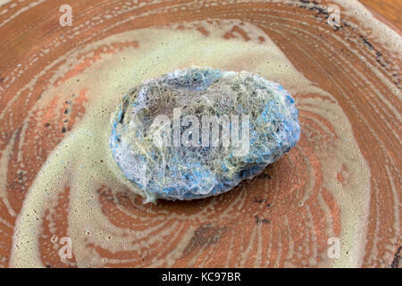 Ansicht schließen einer seifigen Edelstahl Scheuerschwämme verwendet für die Reinigung auf alten Kupfer Pfanne. Stockfoto