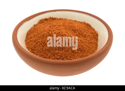 Seitenansicht eines kleinen roten Ton Schüssel mit einem Teil der Taco seasoning auf einem weißen Hintergrund. Stockfoto