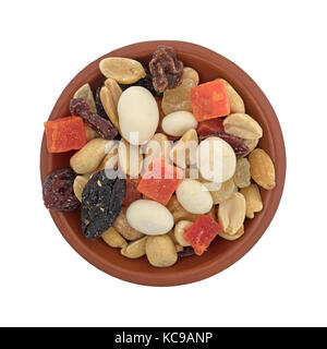 Ansicht von oben in einem kleinen roten Ton Schüssel mit Joghurt, Rosinen, Obst und Mutter trail Mix auf einem weißen Hintergrund. Stockfoto