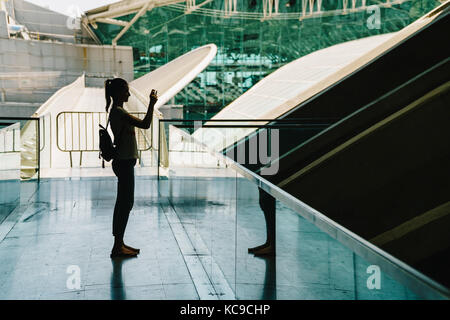 Silhouette gegen Licht der jungen Frau Fotografieren in modernes Gebäude Stockfoto