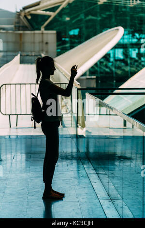 Silhouette gegen Licht der jungen Frau Fotografieren in modernes Gebäude Stockfoto