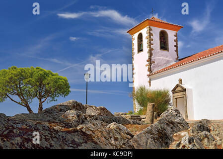 Mittelalterliche weiß gewaschene Kirche mit Felsen, Baum und blauem Himmel Stockfoto