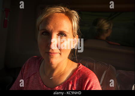 Eine junge weibliche Landwirt sitzt IN EINEM JOHN DEERE MÄHDRESCHER VOR DER ERNTE VON WEIZEN AUF DEM BAUERNHOF DER FAMILIE IN DER NÄHE VON BRECKENRIDGE, NORTH DAKOTA Stockfoto