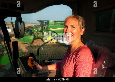 Eine junge weibliche Landwirt sitzt IN EINEM JOHN DEERE MÄHDRESCHER VOR DER ERNTE VON WEIZEN AUF DEM BAUERNHOF DER FAMILIE IN DER NÄHE VON BRECKENRIDGE, NORTH DAKOTA Stockfoto