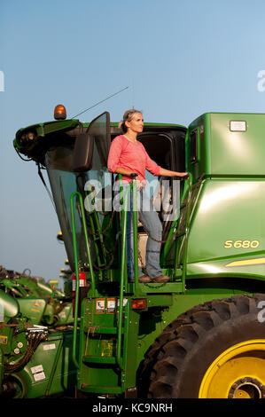 Eine junge weibliche BAUER BLICKT AUF DEM GEBIET VON IHREM JOHN DEERE MÄHDRESCHER VOR DER ERNTE VON WEIZEN AUF DEM BAUERNHOF DER FAMILIE IN DER NÄHE VON BRECKENRIDGE,DAKOT Stockfoto