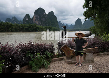 Chinesischer Junge mit Kormorane für Erinnerungsfoto posiert, asiatische Kind auf Urlaub. natürliche Landschaft und Li River in der Nähe von xingping, zwischen Yangshuo und gu Stockfoto