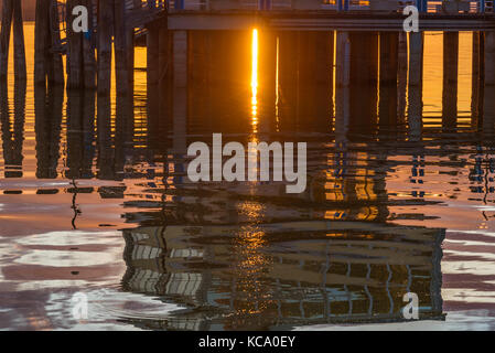 Reflexionen eines Gebäudes im Wasser eines Sees bei Sonnenuntergang. Stockfoto