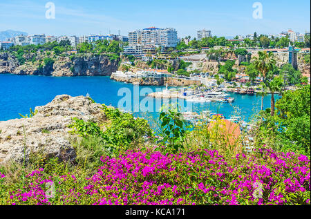 Die hohen Klippen von Antalya und seine alten Marina mit hellen bougainivillea im Vordergrund, mermerli Park, Türkei. Stockfoto