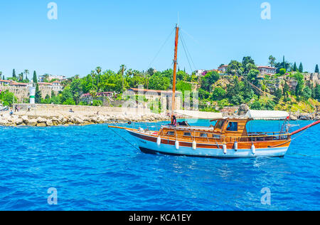 Antalya, Türkei - 13. Mai 2017: die hölzerne Yacht an der Küste von Antalya, Segel, der Hafen, die mittelalterlichen Stadtmauern und Grün des Gartens sind mermerli Stockfoto