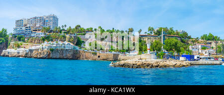 Die felsige Küste von Antalya Altstadt mit Resten der Stadtmauer und moderne Hotels auf der Spitze des Felsens, der Türkei. Stockfoto