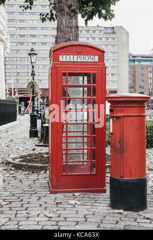 Eine ikonische rote Telefonzelle neben einer roten Briefkasten in St. Katharine Docks, London. Rote Telefonzellen können in aktuellen oder ehemaligen britischen Kolonien gefunden werden Stockfoto