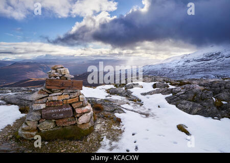Eine Erhaltung Cairn auf Beinn Eighe mit dem Gipfel des Creag Dhubh in der Ferne. Schottische Highlands, Schottland, Großbritannien. Stockfoto
