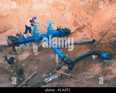 Arbeiter in Sicherheit Kleidung des Ventils Conduit auf Stadt Trinkwasser Leitung mit schwarzer Mehrfachkupplung in alte Pipeline System zusammengefügt. Con Stockfoto