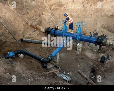 Technische Experten offene Tor Ventil auf 500 mm Wasser trinken Rohre verbunden mit neuen schwarzen besonderen Kuppler in die Stadt. Steuerung überprüfen Stockfoto