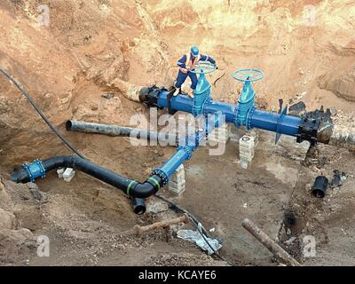 Technische Experten offene Tor Ventil auf 500 mm Wasser trinken Rohre verbunden mit neuen Schwarz Multi spezielle Kupplung in alten Pipeline System. Steuerung überprüfen Stockfoto