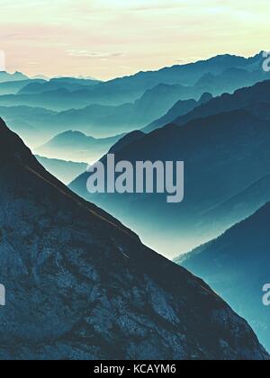 Einen spektakulären Blick auf die Berge Silhouetten und nebligen Täler. misty Erwachen der schönen Fee Tal. Gipfel der Felsen cremige Nebel Wolken schneiden. Stockfoto