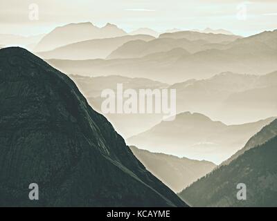 Einen spektakulären Blick auf die Berge Silhouetten und nebligen Täler. misty Erwachen der schönen Fee Tal. Gipfel der Felsen cremige Nebel Wolken schneiden. Stockfoto