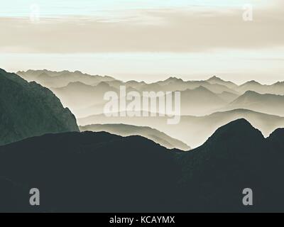 Einen spektakulären Blick auf die Berge Silhouetten und nebligen Täler. misty Erwachen der schönen Fee Tal. Gipfel der Felsen cremige Nebel Wolken schneiden. Stockfoto