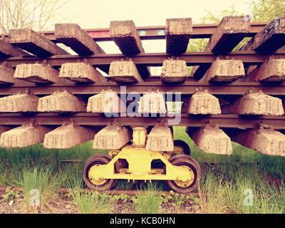 Wagen mit Extrahierten alte Eisenbahnen. Beton- und Holzschwellen mit Rail Stangen im Bahnhof Lager für den Transport zu Stahlgiesserei warten auf rec Stockfoto