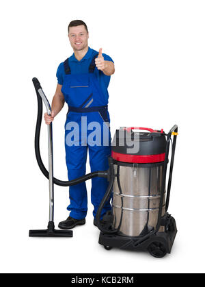 Portrait von jungen männlichen Hausmeister mit Staubsauger, Daumen oben auf weißem Hintergrund Stockfoto