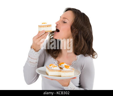 Nahaufnahme einer jungen Frau essen ein Stück Kuchen auf weißem Hintergrund Stockfoto