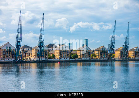 Moderne mews Häuser und Denkmalgeschützte alte Krane mit Blick auf das Royal Victoria Dock auf der Greenwich im Osten von London, England, UK. Stockfoto