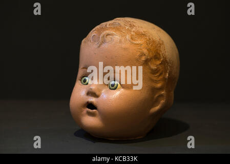 Nahaufnahme des Studios mit Puppenkopf für zusammengesetzte Knaben, geschweiften, geformten Haaren, offenem Mund. Starrende blaue Augen mit Kopierraum im schwarzen Hintergrund Stockfoto