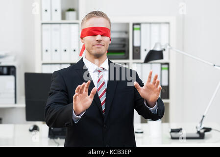 Porträt eines mit verbundenen Augen junger Geschäftsmann Gestik im Büro Stockfoto