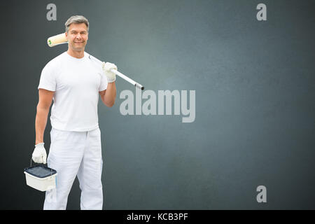 Porträt eines jungen männlichen Maler In weiße Uniform stehend mit Farbroller Stockfoto
