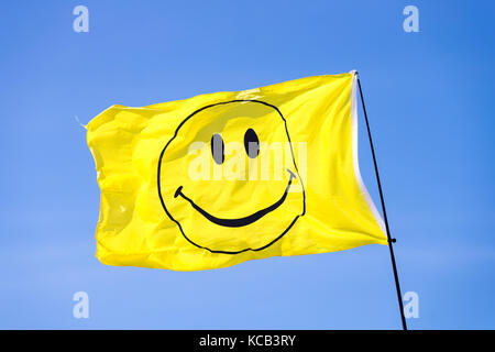 Eine gelbe Smiley Flagge weht im Wind vor blauem Himmel Stockfoto