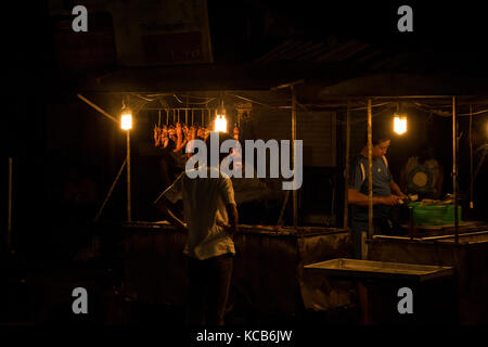 Eine Straße Metzger, mit Fleisch auf Anzeige in seinem Stall, Verkauf von Fleisch in einen jungen männlichen Kunden in den Straßen von Phnom Penh, Kambodscha, SE-Asien. Stockfoto