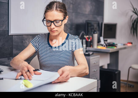 Frau tragen Brillen spät im Büro arbeiten und Schreiben Stockfoto