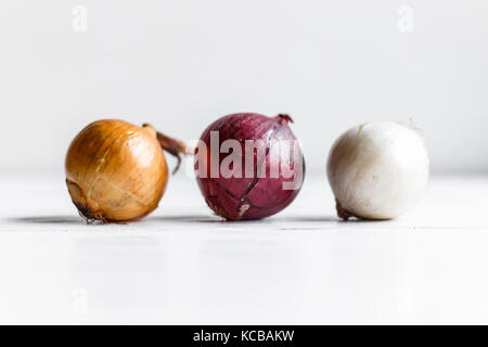Drei Birnen auf einem weißen Hintergrund Holz. weiße Zwiebeln, Zwiebeln und roten Zwiebeln. Stockfoto