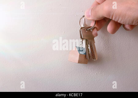 Hände hängenden Tasten mit Schlüsselring an einem Haken an der Wand eines Hauses mit Sonnenschein Stockfoto