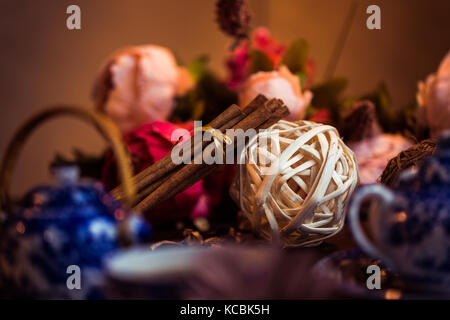 Gemahlener Zimt, Zimtstangen, mit einem Tablett mit einem Bogen auf einem floral background im rustikalen Stil verbunden. Selektive konzentrieren. Essen Konzept. Jahrgang zu Stockfoto